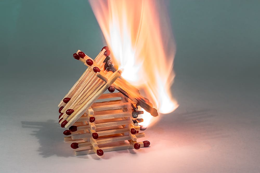 a burning small house made of matchsticks